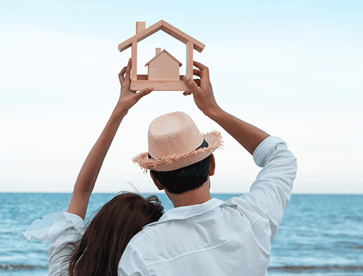 Two individuals holding a wooden house Two individuals holding a wooden house