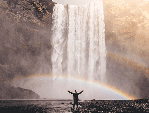 person in front of waterfall with a rainbow person in front of waterfall with a rainbow